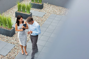 Two business people walking to a meeting and talking about work whilst they walk, the female is holding a digital tablet