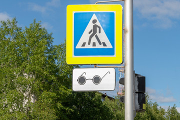 Road sign adjustable pedestrian crossing in blue with a badge for blind pedestrians in the form of black glasses.  Street of the city.  Bottom view front