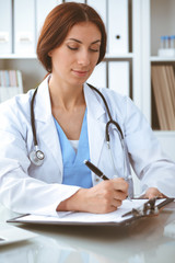 Wall Mural - Doctor woman at work. Physician filling up medical history records form at the desk. Medicine, healthcare concept