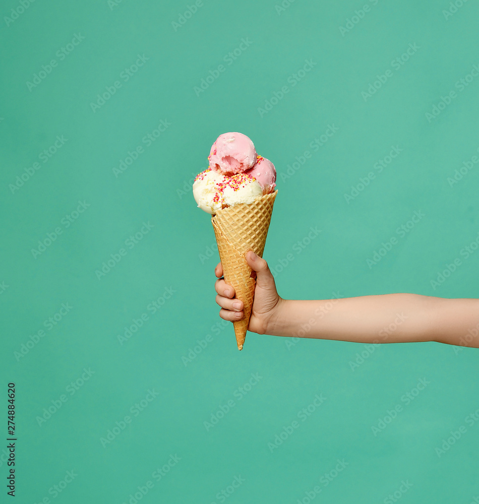 Baby kid hand holding big ice-cream in waffles cone on blue - obrazy, fototapety, plakaty 