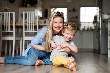 Wall Mural - A happy mother with a toddler son indoors at home. Copy space.