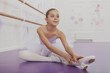 Elegance, achievement concept. Lovely young ballerina stretching at ballet school before dance class, copy space. Charming young preteen ballerina exercising at dance studio