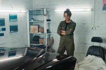 Attractive Caucasian woman looking at her vintage old car in a garage