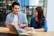 © chayathon2000 - Asian couple in blue shirt drinking coffee talking and working with computer laptop smile and  happy mood in coffee shop cafe
