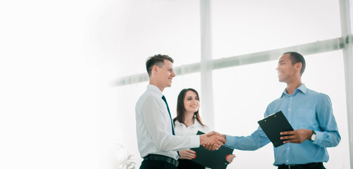 Wall Mural - friendly business people shaking hands on blurred background