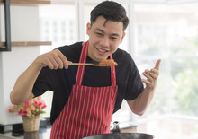 Young Happy Asian Man Cooking And Smelling Delicious Food