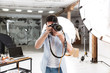 Portrait of young brunette photographer man shooting model with professional camera in studio