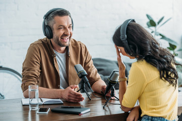 two cheerful radio hosts talking while recording podcast in radio studio