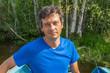 © Tatyana_Andreyeva - Handsome middle-aged man sitting at boat stern and floating along northern river on beautiful landscape background in summer sunny day. Travel concept. Chernaya river, Karelia, Russia