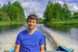 © Tatyana_Andreyeva - Handsome middle-aged man sitting at boat stern and floating along northern river on beautiful landscape background in summer sunny day. Travel concept. Chernaya river, Karelia, Russia