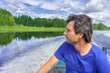 © Tatyana_Andreyeva - Handsome middle-aged man sitting at boat stern, floating along northern river and relaxing on beautiful landscape background in summer day. Travel concept. Chernaya river, Karelia, Russia