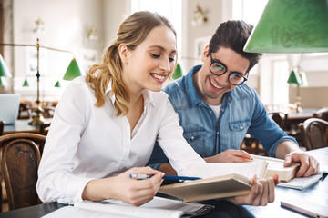 Canvas Print - Smart cheerful teenagers studying at the library together