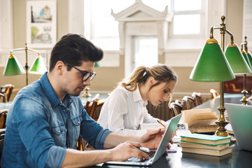 Sticker - Smart cheerful teenagers studying at the library together