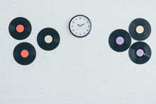 Vinyl Discs And Round Clock On White Brick Wall