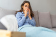 Woman with an inhaler. Portrait of a young woman doing inhalation at home. Use nebulizer and inhaler for the treatment. Young woman inhaling through inhaler mask lying on the couch