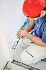 Wall Mural - Worker using silicone for walls and door frame inside the house - renovation fixes.