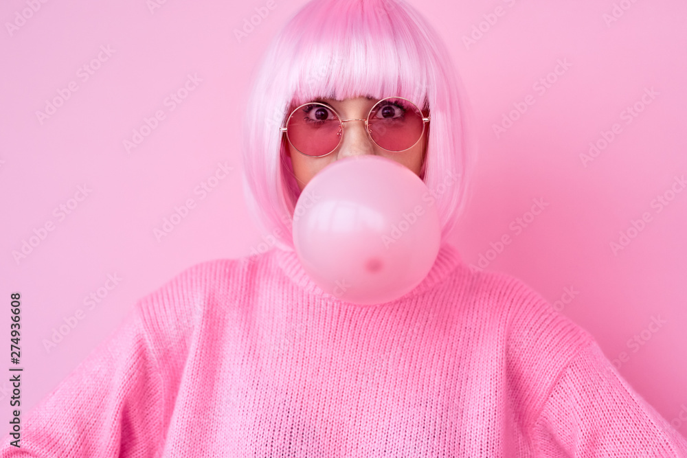 Young woman in pink outfit blowing gum - obrazy, fototapety, plakaty 