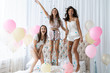© opolja - Yeah! Four attractive young women in pajamas smiling and gesturing while jumping in the bedroom with confetti flying everywhere