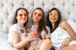 © opolja - Pajama party. Attractive young smiling women in pajamas drinking champagne while having a slumber party in the bedroom.