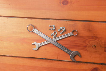 Two wrenches and some bolts are laying on a wooden surface