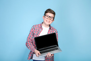 Wall Mural - Young boy holding a laptop on blue background