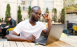 © proimagecontent - African smart student browsing articles at the Internet while sitting at the outdoor cafe