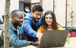 © proimagecontent - Three multicultural students discussing something at the laptop while studying at the cafe