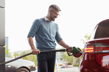 Smiling man refueling car in city