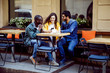 © proimagecontent - Three multicultural happy friends having a coffee time at the outdoor cafe