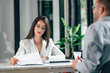 © bnenin - Elegant financial adviser looking at documents on a meeting with a client.