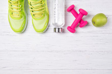 Fitness Concept, Green Sneakers, Pink Dumbbells, Bottle Of Water And Green Apple On A Wooden Background, Top View, Healthy Lifestyle