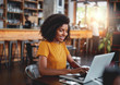 © StratfordProductions - Young woman in café typing on laptop