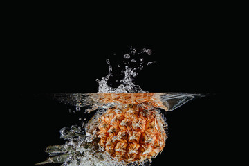 Canvas Print - Fresh and delicious pineapple isolated against dark, black background. Pineapple dropping in water and creating a splash. The concept of healthy eating, consuming fruit.