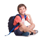 Happy Smiling School Boy Siitting On The Floor, Isolated On A White Background