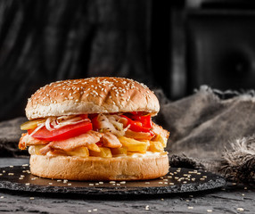 Canvas Print - Chicken burger with tomatoes, french fries and sauce on black slate over dark background. Unhealthy food