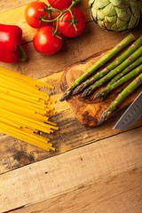 Wall Mural - Asparagus, and an artichoke a sprig of tomatoes and sweet red pepper and Italian spaghetti on a cutting board with a knife, sliced. tasty and healthy food, restaurant menu, homemade menu.