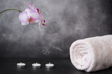 White And Pink Moth Orchid Flowers, Towel, And Three Candles On Grey Background