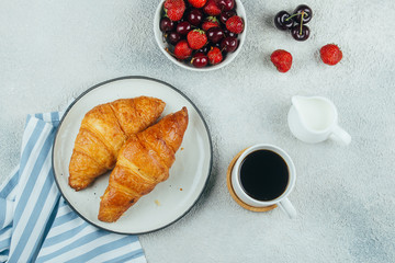 Wall Mural - Delicious breakfast food concept. Coffee, croissants and berries for breakfast on light concrete background. Top view, flat lay