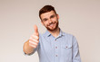 Portrait of handsome guy with thumb up on studio background