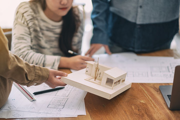 Wall Mural - Group of an architect working and discussing about an architecture model together with shop drawing paper on table in office