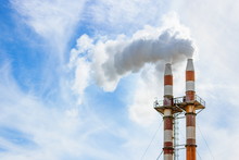 Close Up Image Of Two Smoke Stacks Billowing Smoke Into The Atmosphere Against Blue Sky With Copy Space