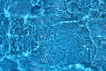 Blue and bright water surface with sun refection in swimming pool for background