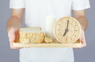 Man with white T Shirt holding breakfast (Bread and milk bottle) serve in wooden plate