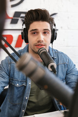 Wall Mural - Young man radio host with colleague woman at the workspace with microphone and sound equipment talking with each other.