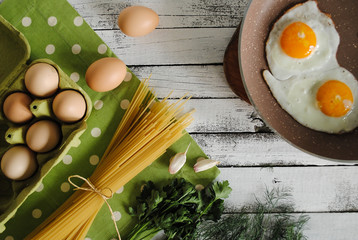 Wall Mural - Eggs in a pan and vegetables with pasta on a white background