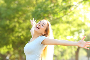 Happy teenage girl stretching arms in a park