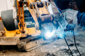 Wall Mural - Industrial machinery being rapaired on construction site. mechanic welder working on excavator