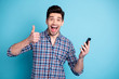 © deagreez - Photo portrait of excited crazy delightful rejoicing handsome lucky triumphing he him guy using getting new version of telephone hold hand give finger up isolated pastel background