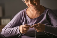 Senior Woman Knitting At Home Late In Evening