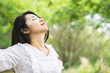 happy Asian woman arms up and breathing deep outdoors and relaxing with nature background 